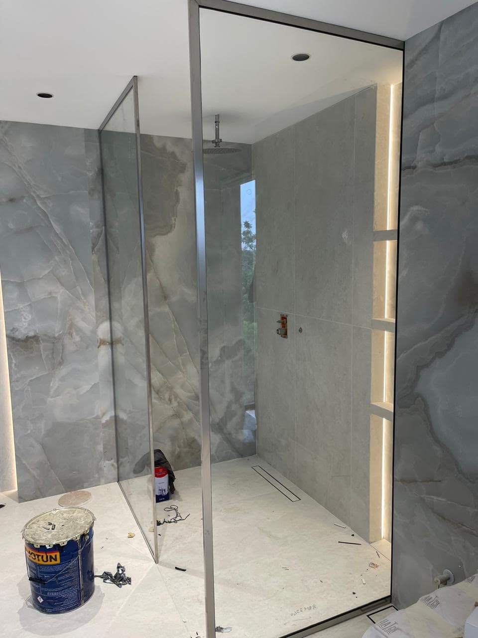 Frameless glass shower enclosure with marble walls