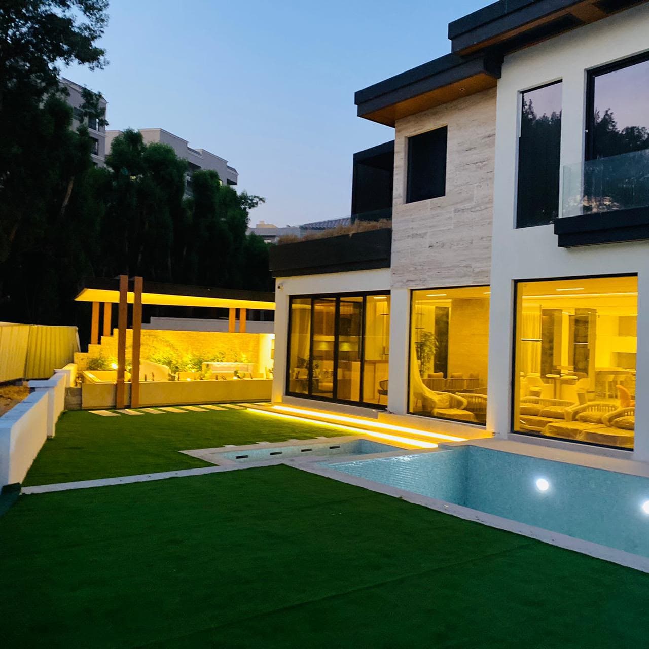 Villa terrace with an aluminium pergola and glass sliding doors at dusk